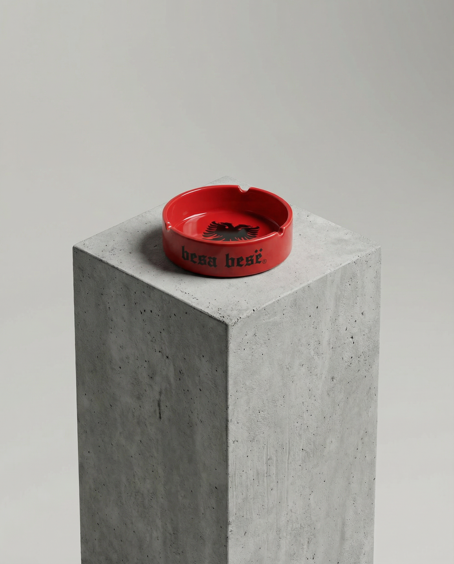 Red ashtray with 'best' text on a concrete block against a gray background