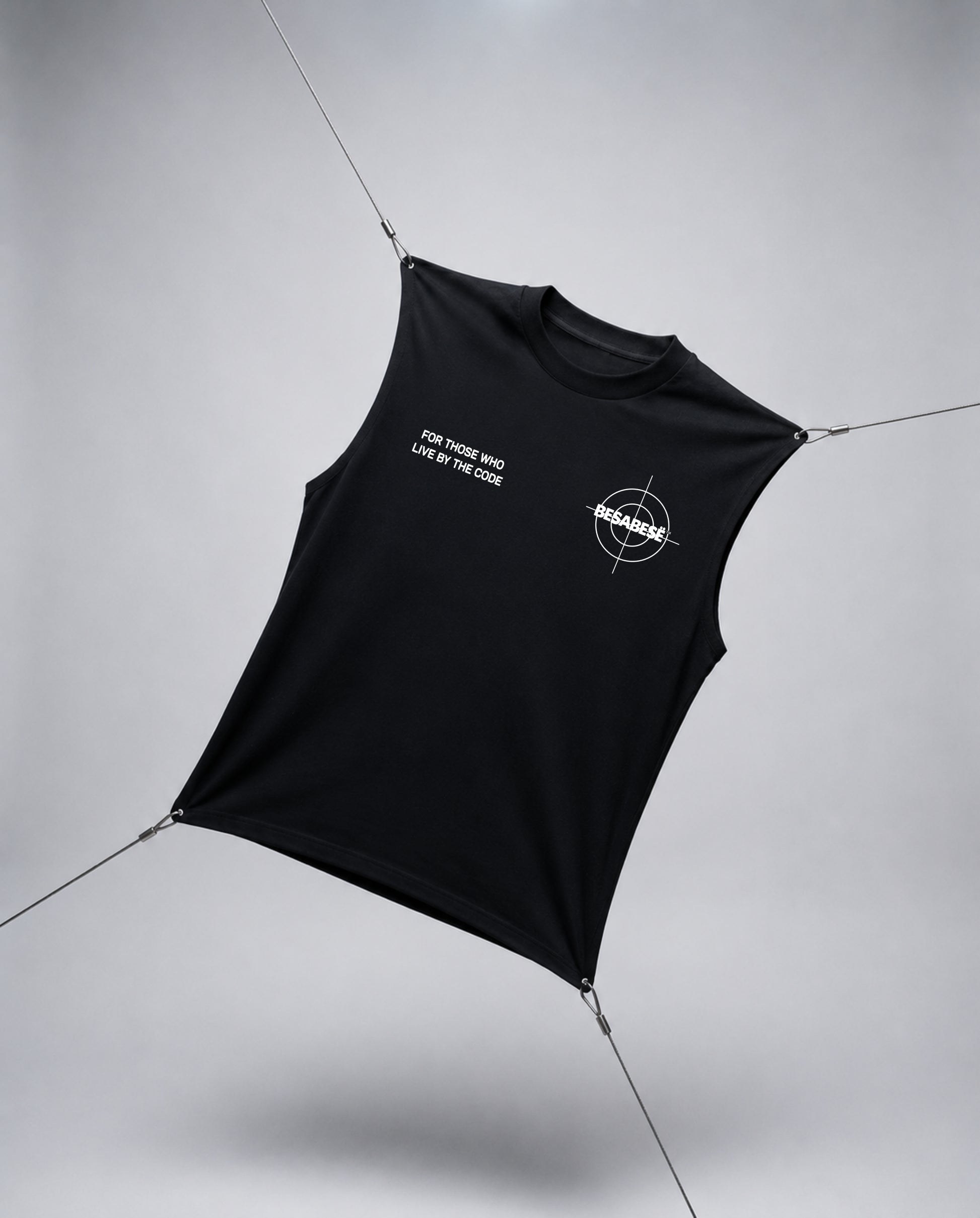 A black sleeveless crop top with white printed graphics, suspended by thin wires against a light gray studio background.