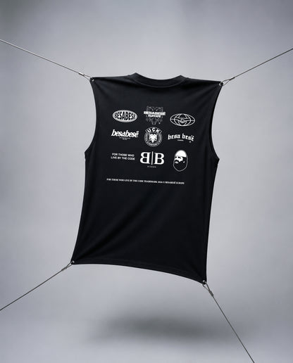 A black sleeveless crop top with a white graphic print featuring multiple logos and text, suspended by thin cables against a gray studio background.