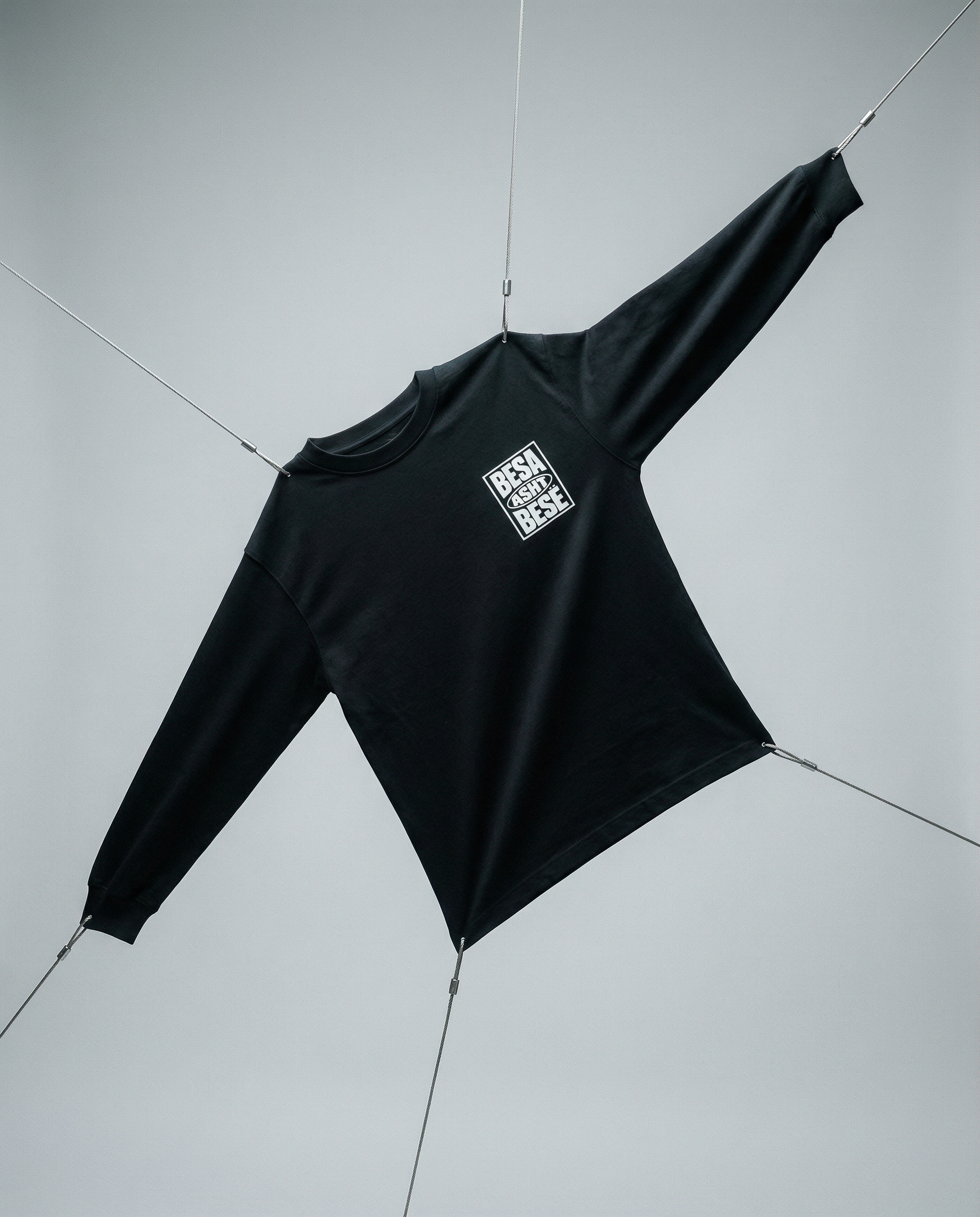 Black long-sleeve shirt with a logo on a light gray background