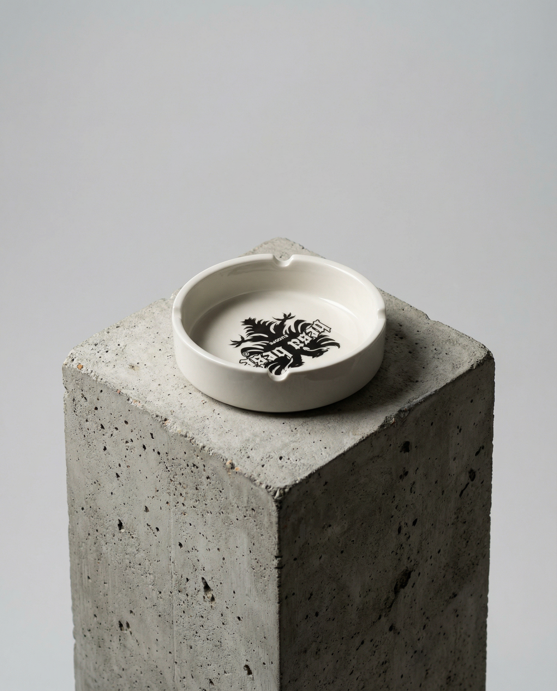 Ceramic ashtray with a logo on a concrete block against a gray background