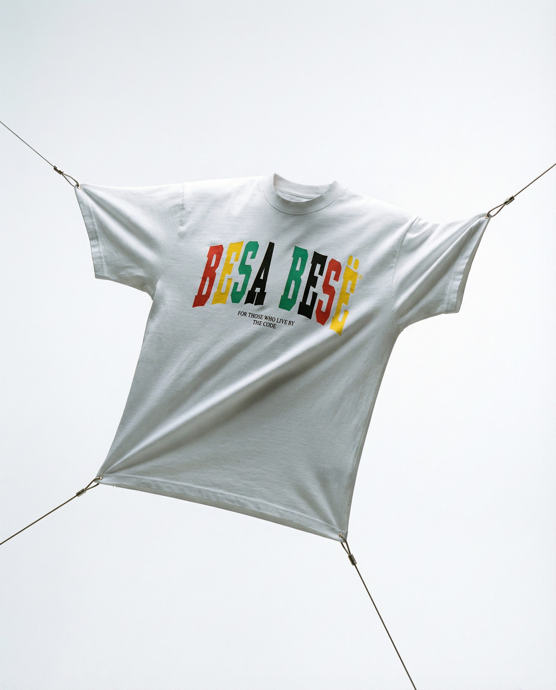 White t-shirt with colorful text 'BESA BESE' hanging on a line against a white background