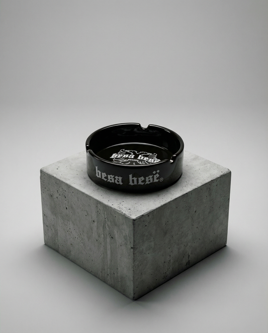 Black ashtray with 'hess hess' branding on a concrete block against a gray background