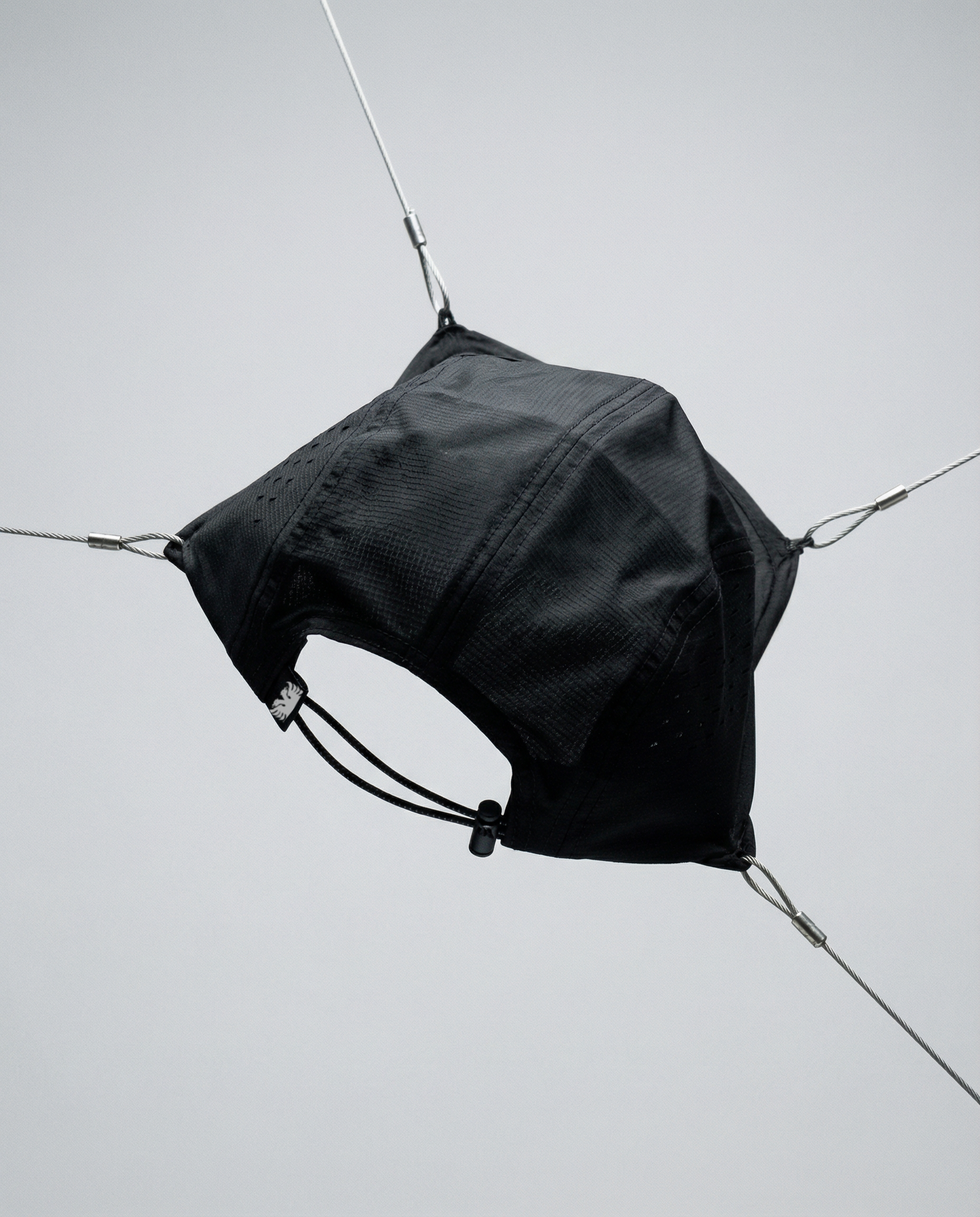 Black bag hanging from a wire against a light gray background