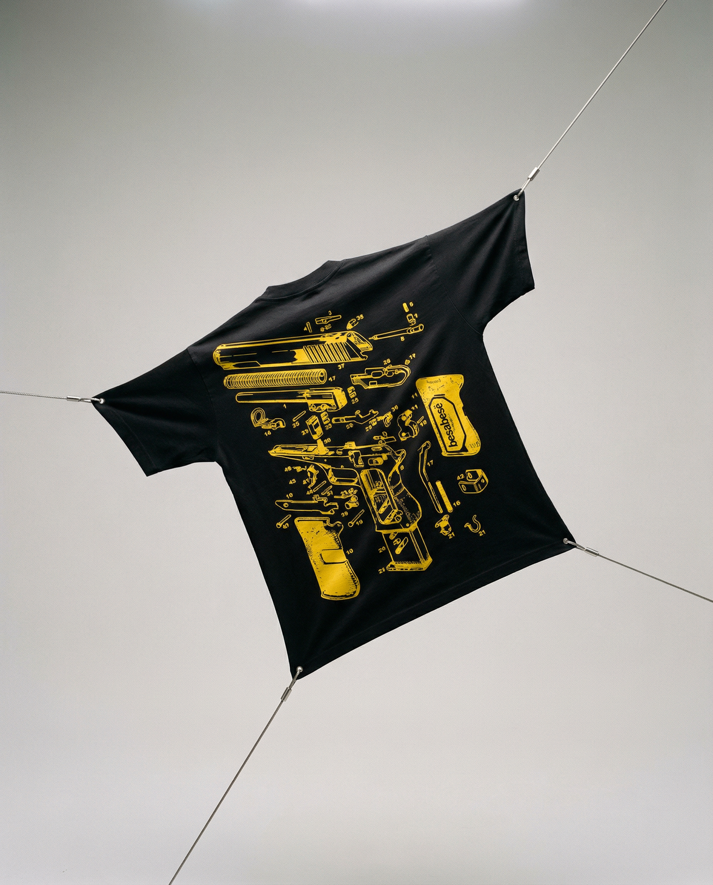Black t-shirt with yellow graphic design on a white floor