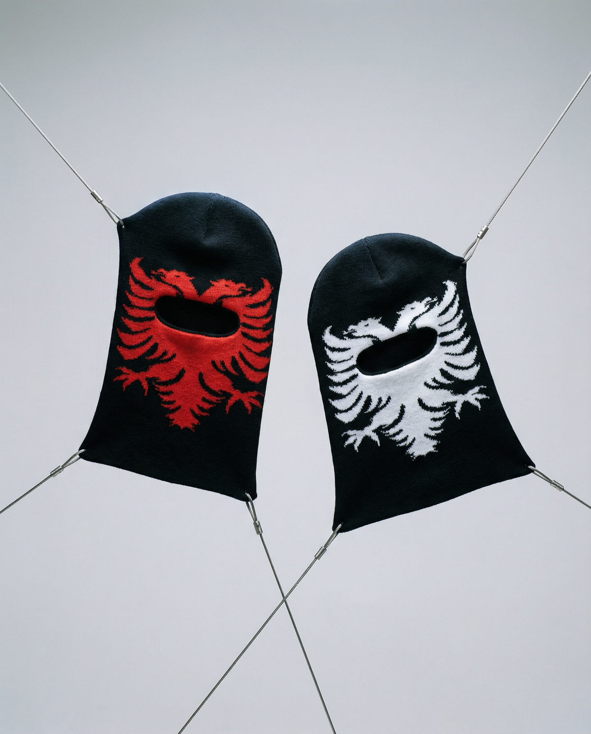 Two black beanies with red and white eagle designs on a light gray background